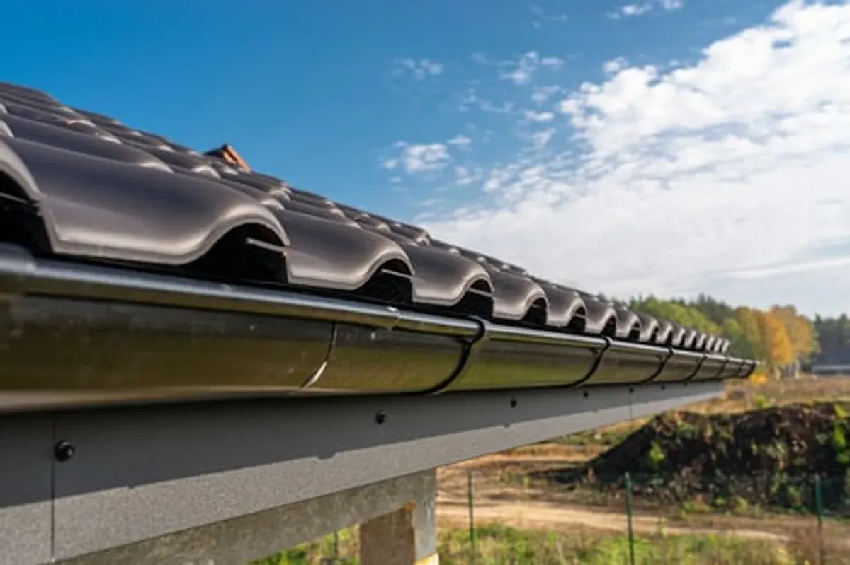 Clean seamless gutter system along the edge of a residential roof against a blue sky