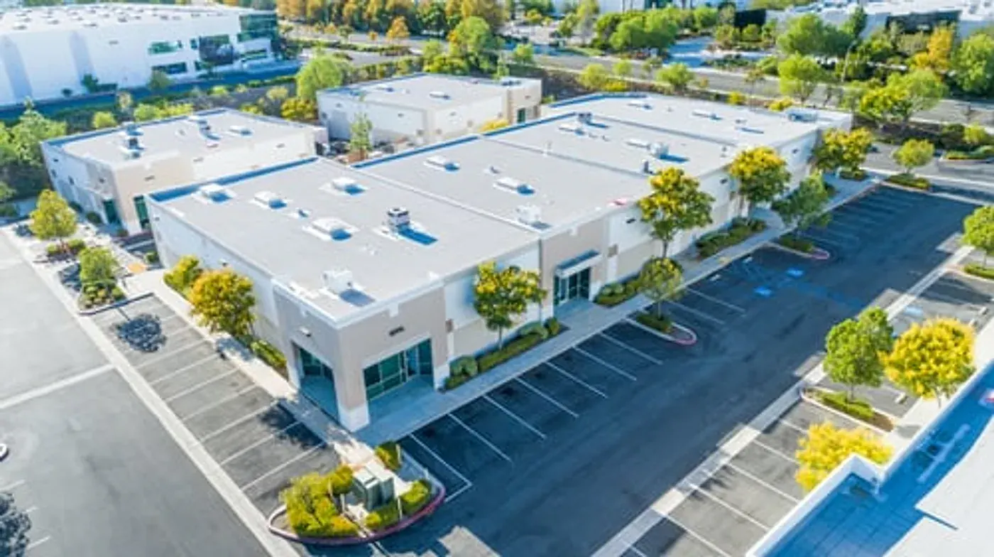 Aerial view of a commercial building with a newly installed white TPO flat roofing system in Georgia